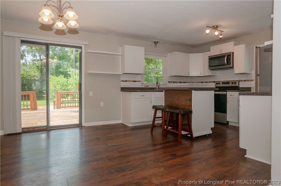 4605 Nix Road Fayetteville, NC 28314 - Photo 21 of 48 a kitchen with stainless steel appliances granite countertop a stove top oven a refrigerator a sink and a dining table with wooden floor