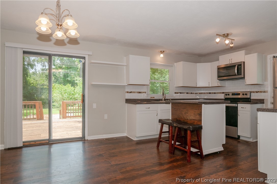 4605 Nix Road Fayetteville, NC 28314 - Photo 23 of 48 a kitchen with stainless steel appliances granite countertop a stove top oven a sink dishwasher a dining table and chairs with wooden floor