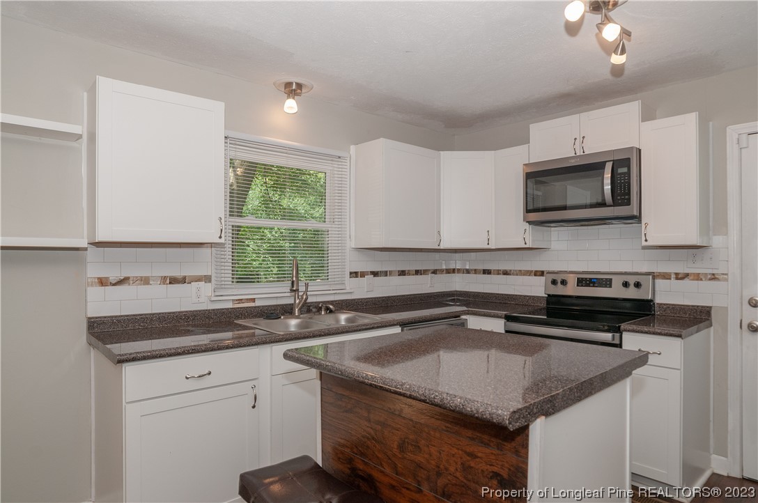 4605 Nix Road Fayetteville, NC 28314 - Photo 25 of 48 a kitchen with a sink dishwasher a stove and a microwave oven with cabinets
