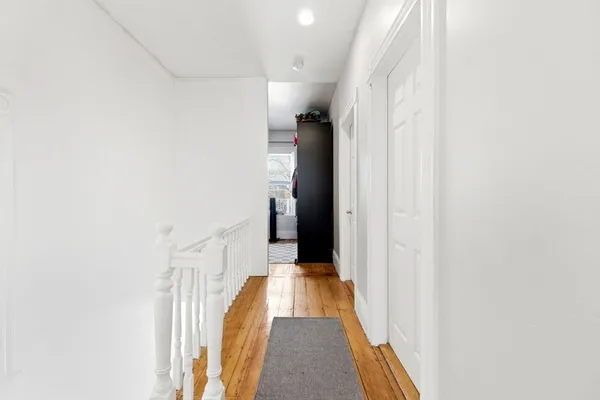 a view of a hallway with wooden floor and staircase
