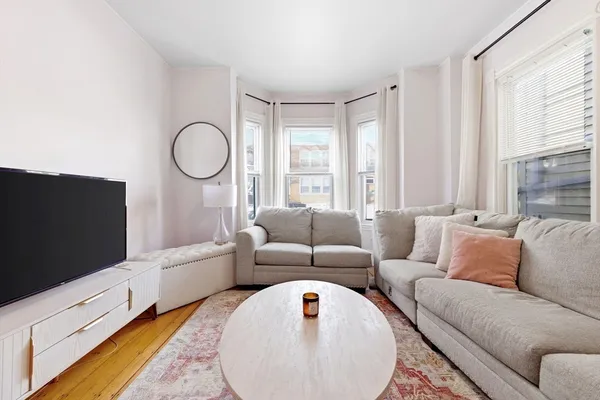 a living room with furniture a flat screen tv and a window