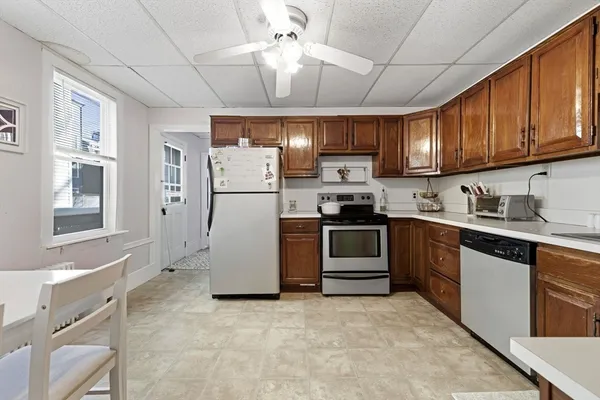 a kitchen with stainless steel appliances granite countertop a refrigerator a stove a sink dishwasher and white cabinets with wooden floor