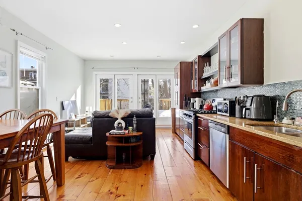 a large living room with stainless steel appliances granite countertop a stove a sink a couch and a dining table