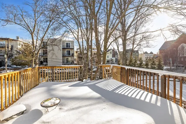 a view of a roof deck with wooden fence and trees