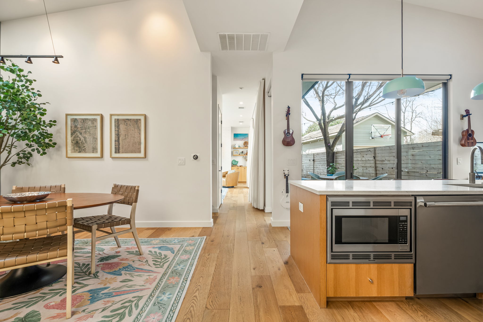 1811 Collier Street Austin, TX 78704 - Photo 8 of 40 Kitchen with pendant lighting, stainless steel appliances, light wood-style floors, a high ceiling, and light stone counters