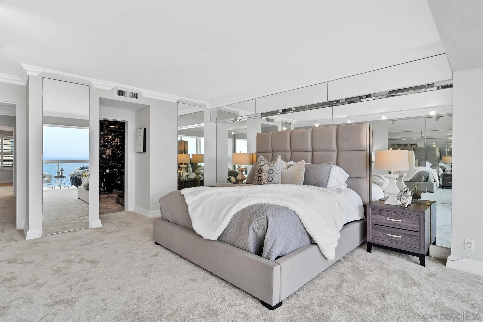 939 Coast Boulevard, Unit 12C La Jolla, CA 92037 - Photo 21 of 41 a spacious bedroom with a bed and a mirror