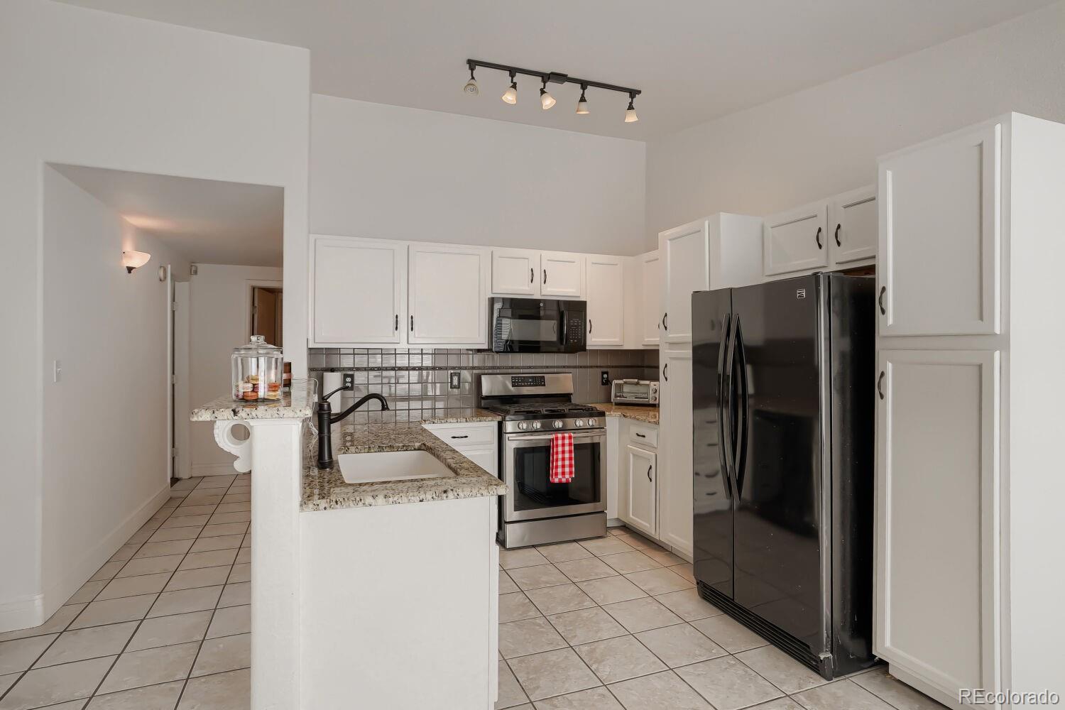 8437 South Thunder Ridge Way, Unit 204 Highlands Ranch, CO 80126 - Photo 6 of 27 a kitchen with a refrigerator a microwave oven and a sink