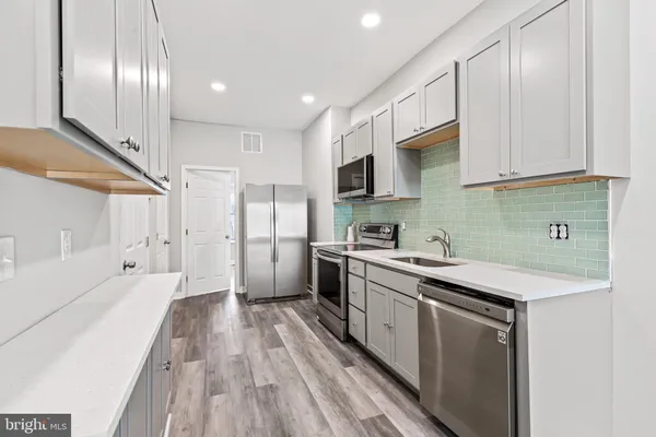 a kitchen with a sink a counter top space stainless steel appliances and cabinets