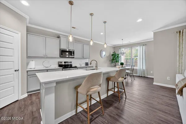 a kitchen with stainless steel appliances granite countertop a stove a refrigerator a sink a dining table and chairs with wooden floor