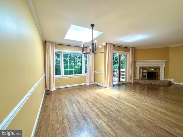 an empty room with wooden floor fireplace and windows