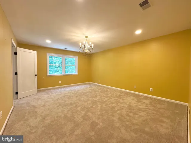 a view of an empty room with a chandelier fan and a window
