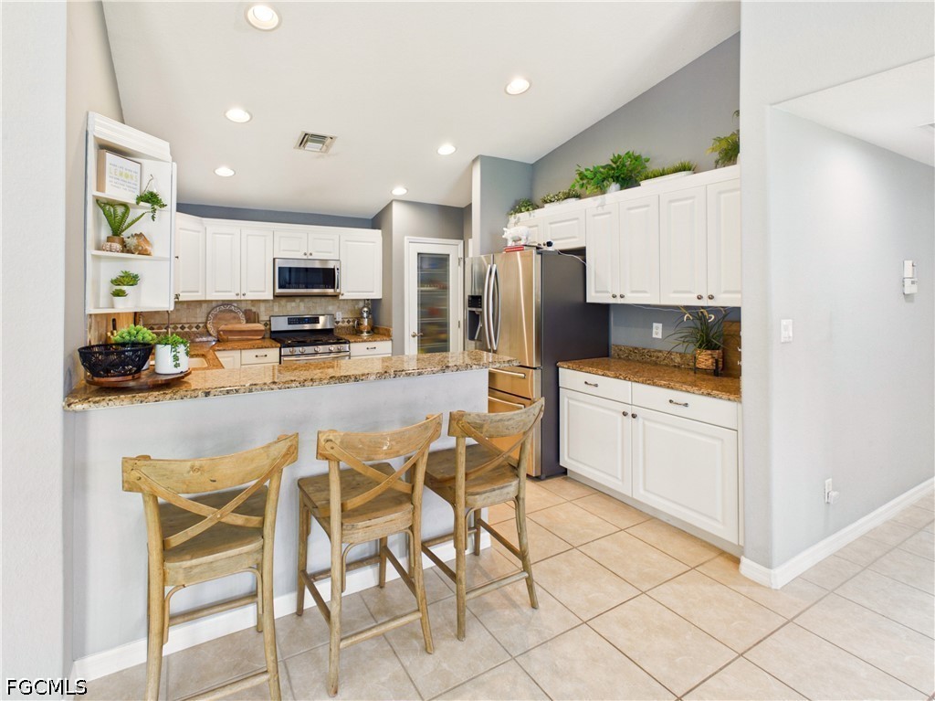 19694 Villa Rosa Loop Estero, FL 33967 - Photo 10 of 28 a kitchen with stainless steel appliances kitchen island granite countertop a refrigerator and microwave