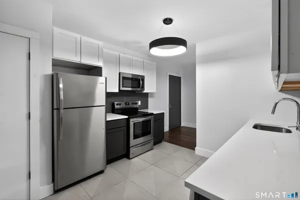 a kitchen with stainless steel appliances granite countertop a refrigerator a stove a sink and a microwave