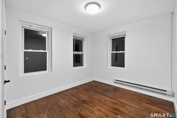 a view of an empty room with wooden floor and windows