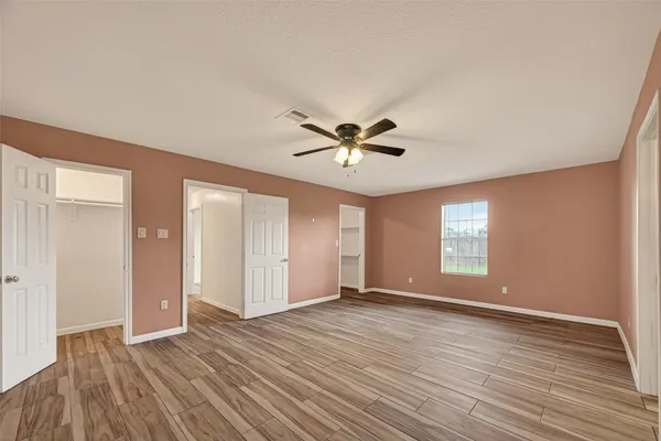a view of empty room with wooden floor and fan