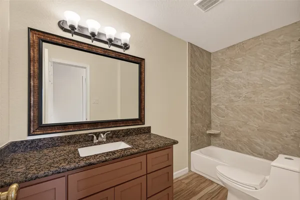a bathroom with a granite countertop toilet sink and mirror