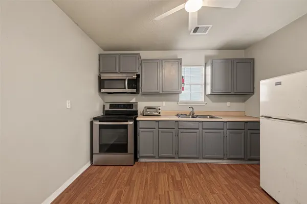 a kitchen with granite countertop a refrigerator stove top oven and sink