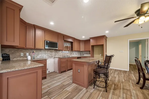 a kitchen with granite countertop kitchen island stainless steel appliances a sink and cabinets