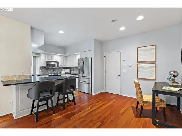 a kitchen with stainless steel appliances kitchen island granite countertop a dining table chairs and granite counter tops