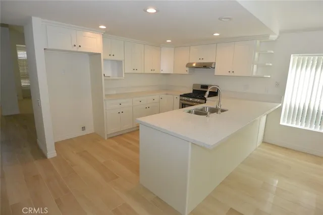 a kitchen with a sink a stove a refrigerator and white cabinets