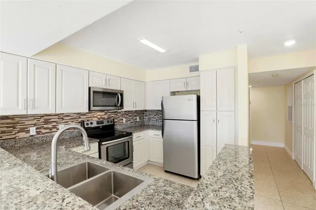 a kitchen with stainless steel appliances granite countertop a sink a stove a refrigerator a washer and dryer