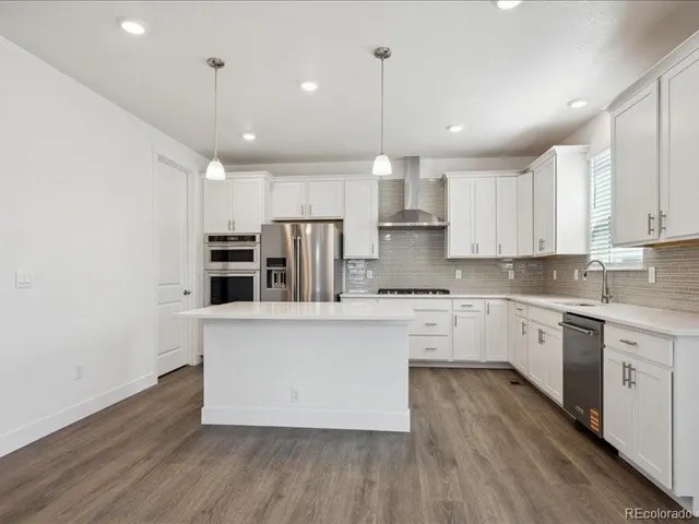 a kitchen with stainless steel appliances granite countertop a sink a stove a refrigerator and white cabinets