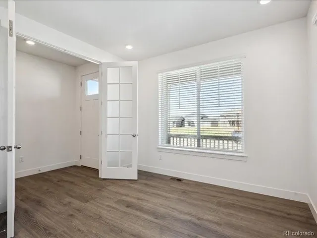 an empty room with wooden floor and windows
