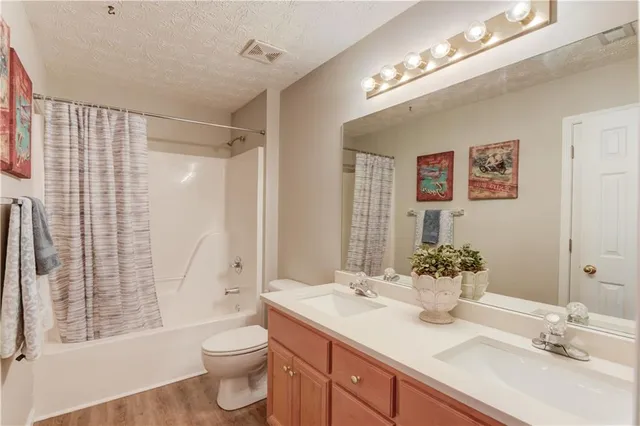 a bathroom with a granite countertop sink toilet a large mirror a shower and a bathtub