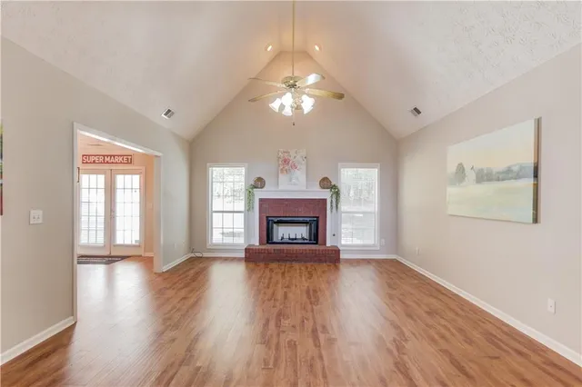 a view of an empty room with wooden floor fireplace and a window