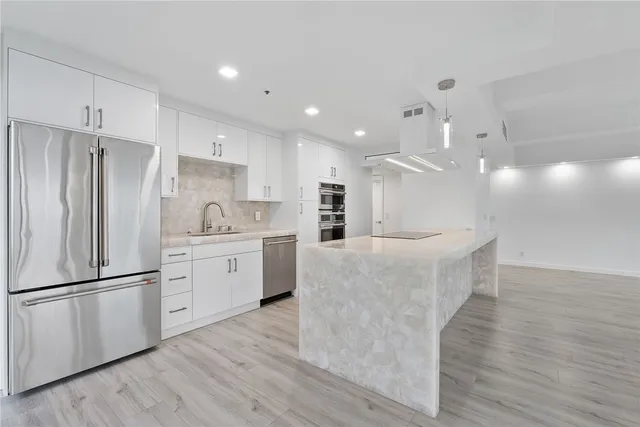 a kitchen with stainless steel appliances kitchen island wooden floors and white cabinets