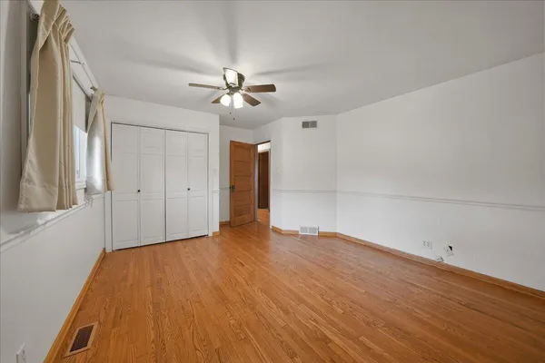 a view of empty room with wooden floor and fan