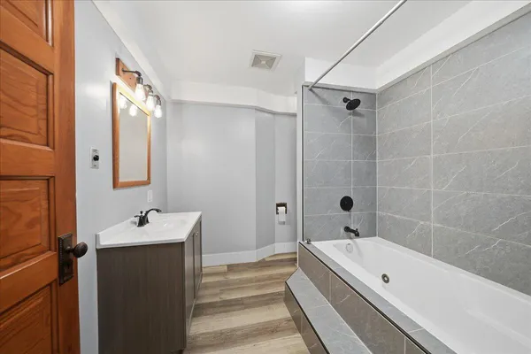 a bathroom with a tub a sink and mirror