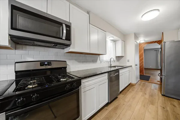 a kitchen with stainless steel appliances a sink a stove and microwave