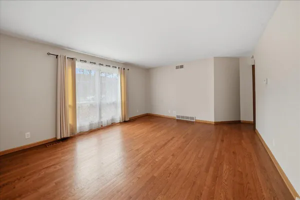 a view of an empty room with wooden floor and a window