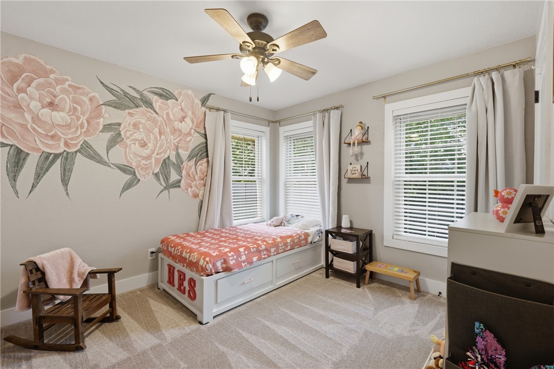 515 Crescent Drive Bryan, TX 77801 - Photo 25 of 43 Neutral wall paint with large-scale floral wall art, dual windows with blinds and curtains, and a ceiling fan with integrated lighting