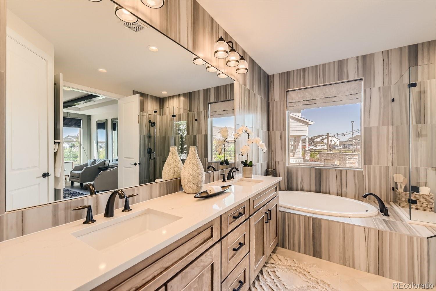 14163 Kearney Loop Thornton, CO 80602 - Photo 15 of 35 a bathroom with a double vanity sink a mirror and a bathtub