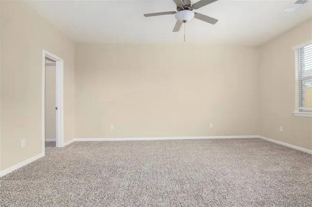 an empty room with closet and a ceiling fan