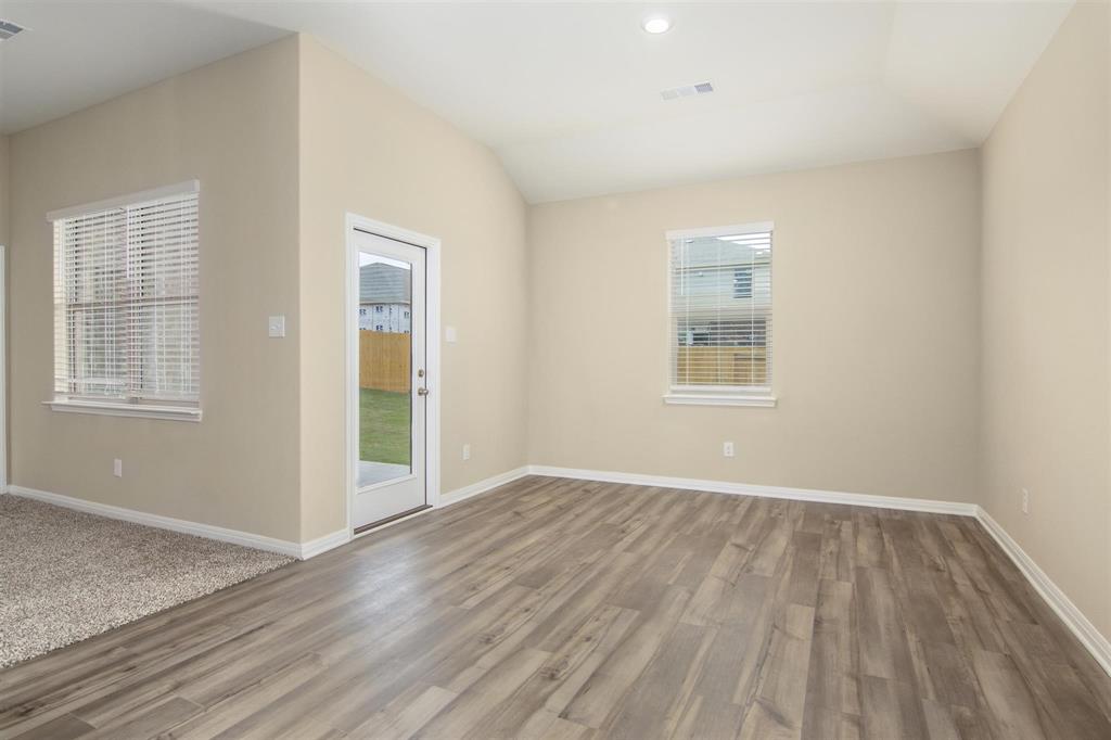 248 Enchanted Way Princeton, TX 75407 - Photo 22 of 24 an empty room with wooden floor and windows