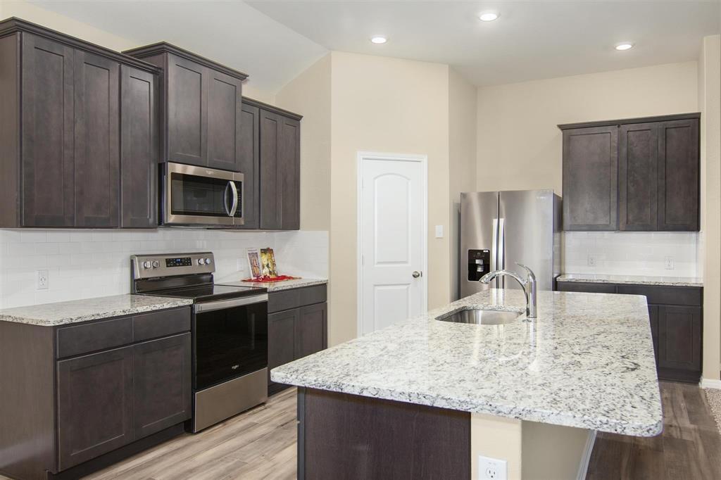 248 Enchanted Way Princeton, TX 75407 - Photo 7 of 24 a kitchen with stainless steel appliances granite countertop a sink refrigerator and microwave