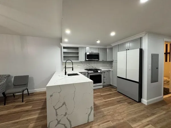 a kitchen with stainless steel appliances kitchen island granite countertop a refrigerator stove top oven and sink