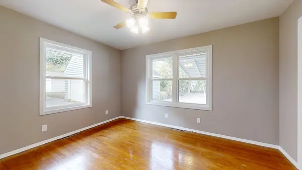 a view of an empty room with a window and wooden floor