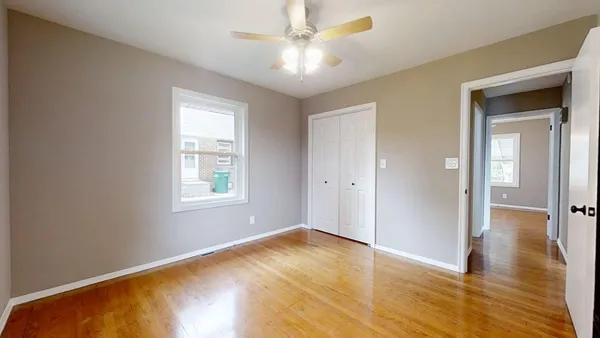 a view of an empty room with window and wooden floor