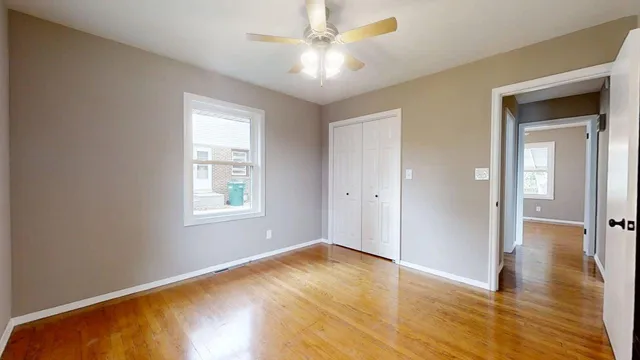 a view of an empty room with window and wooden floor