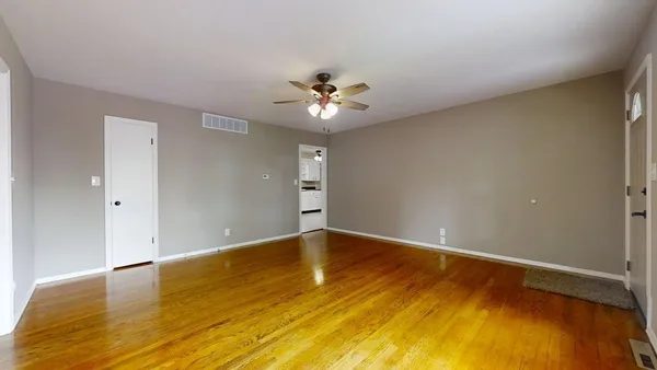 an empty room with a ceiling fan and wooden floor