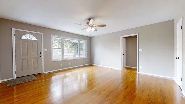 a view of empty room with wooden floor and fan