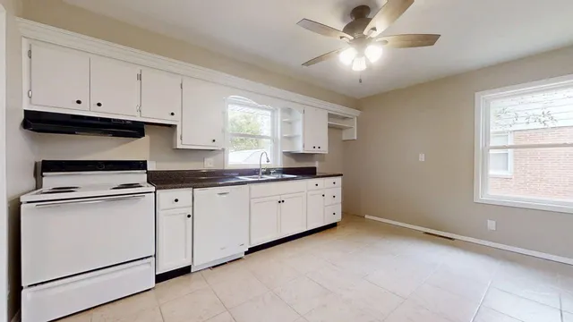 a kitchen with cabinets appliances a sink and a window