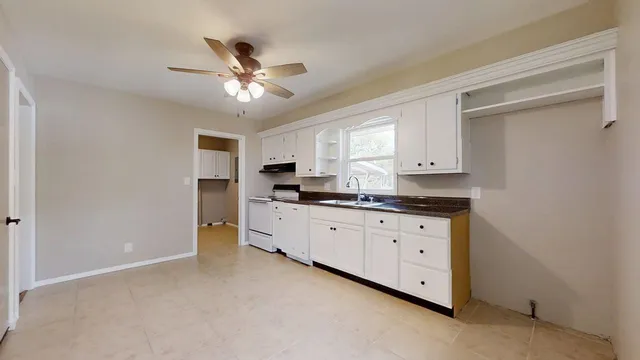a kitchen with granite countertop a sink cabinets stainless steel appliances and a window