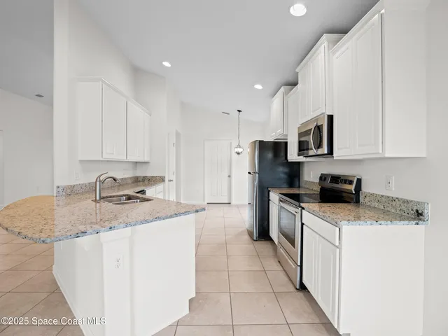 a kitchen with stainless steel appliances granite countertop a sink dishwasher stove and white cabinets