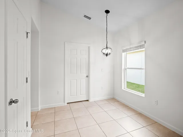 a view of an empty room with window and chandelier fan