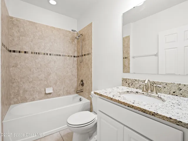 a bathroom with a granite countertop sink toilet mirror and bathtub